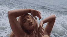 a naked woman is laying in the water with her hands on her head