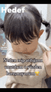 a little girl with pigtails is being held by a person in a video that says hedef