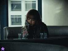 a woman sits on a couch with a glass of water