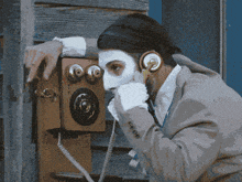 a man with a face painted white is talking on a phone