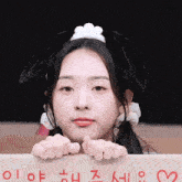 a girl wearing bunny ears is holding a cardboard sign with korean writing on it