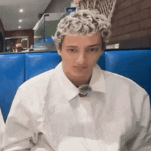a young man with curly blonde hair is sitting in a blue booth .