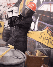 a man wearing a hard hat with the word ara on it is standing in front of a graffiti wall