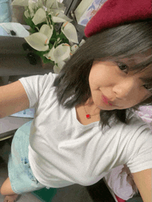 a woman in a white shirt and a red hat takes a selfie