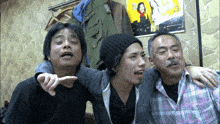 three men are posing for a picture in front of a wall with a painting on it that says ' a ' on it