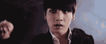 a close up of a young man 's face with a surprised look on his face in a dark room .
