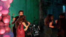 a group of people are dancing in front of a green wall
