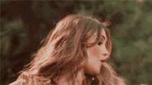 a close up of a woman 's face and hair with trees in the background