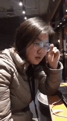 a woman wearing glasses is sitting at a table in a dark room