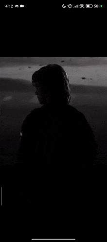 a black and white photo of a person standing in the dark on a cell phone screen .