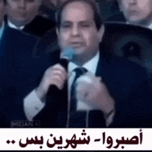 a man in a suit and tie is speaking into a microphone ..