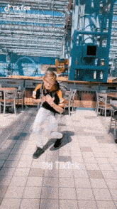 a man is dancing on a tiled floor in front of tables and chairs .