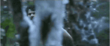 a man wearing a headset is standing in front of a waterfall in the woods .