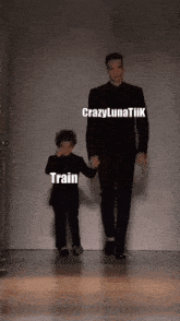 a man and a little boy are walking down a runway and the little boy is holding the man 's hand and says train