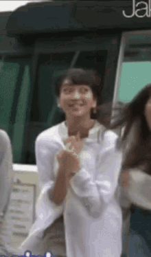 a woman in a white shirt is standing in front of a bus with the word jal on it