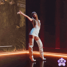 a woman in a white dress and white boots is dancing in front of a screen that says " look at lalisa " on it