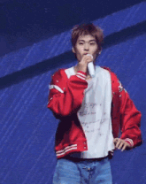 a man wearing a red jacket and a white shirt is holding a microphone