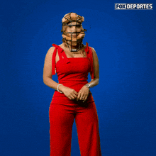 a woman in a red jumpsuit is jumping in front of a blue fox deportes logo