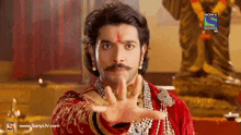 a man with a mustache and a red bindi on his forehead stands in front of a sony television ad