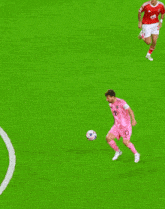 a soccer player wearing a pink jersey tries to steal the ball from another player wearing a red jersey