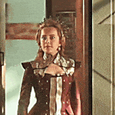 a woman in a red dress with a crown on her head stands in a doorway
