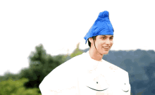 a man wearing a blue hat is standing in front of trees
