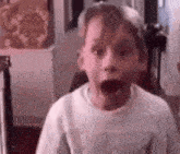 a young boy is making a funny face with his mouth wide open .
