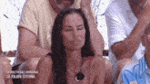 a woman with her eyes closed is sitting in a crowd of people .