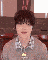 a young man wearing ear buds and a sweater with a yellow chicken on it has his tongue hanging out