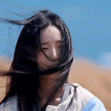 a woman with her hair blowing in the wind looks at the camera