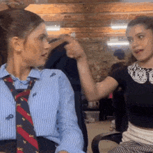 two women are sitting next to each other and one is wearing a striped shirt and tie