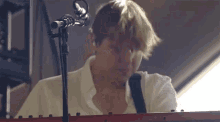 a man is playing a keyboard in front of a microphone