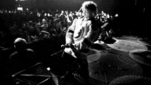 a black and white photo of a person on a stage with a crowd watching