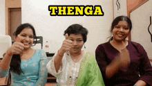 three women are giving a thumbs up in front of a sign that says ' thenga '