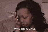a woman is sitting on a couch smoking a cigarette and talking on a cell phone .