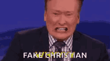 a man in a suit and tie is making a funny face and says `` fake christian '' .