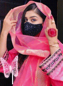 a woman wearing a pink dress and a black mask
