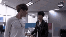 two men are standing next to each other in a room and talking to each other .