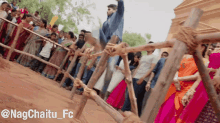 a group of people standing behind a wooden fence with the hashtag nagchaitu_fc at the bottom