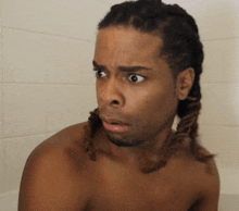 a shirtless man with dreadlocks is looking at the camera with a surprised look on his face
