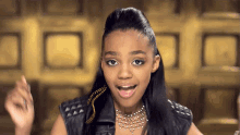 a young girl wearing a necklace and a leather jacket looks at the camera