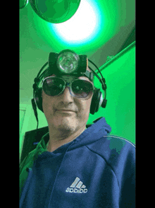 a man wearing headphones and sunglasses has an adidas logo on his shirt