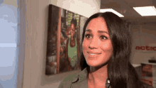 meghan markle is smiling in front of a painting on the wall .