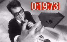 a man in a suit and tie is sitting at a table talking on a phone .
