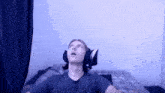 a man wearing headphones is sitting on a bed .