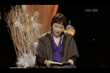 a woman is reading a book in front of a kbs1 hd logo