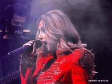 a woman in a red jacket singing into a microphone with anahioverdose written on the bottom right