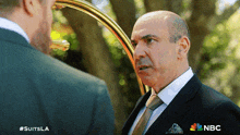 a man in a suit is talking to another man in a suit and tie .