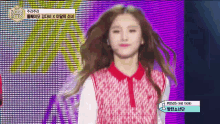 a woman in a red and white dress is standing on a stage in front of a colorful screen .