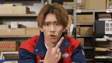 a man in a red and blue jacket is giving a middle finger